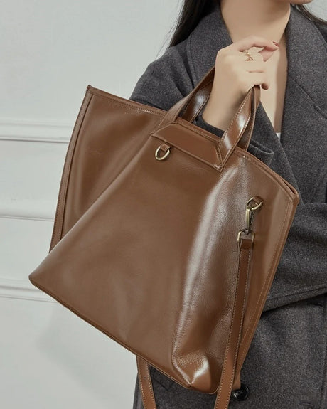 Person holding a brown leather handbag 