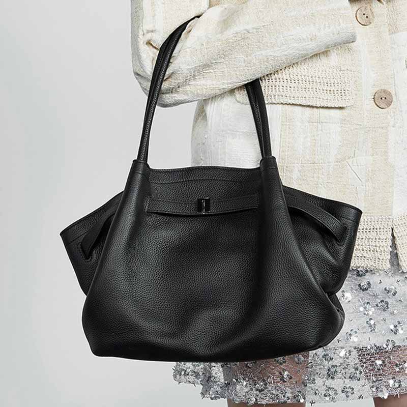 Black Genuine Leather handbag held by a person 