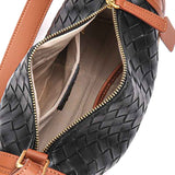Black woven handbag with brown accents and gold zipper, open to show interior.
