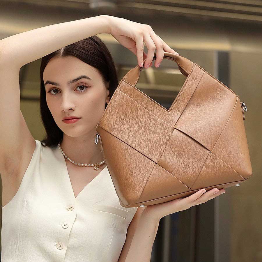 Woman holding a khaki woven handbag 