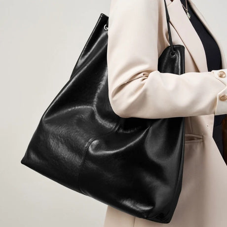 Person holding a black leather tote bag 